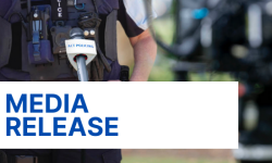 Image of police officer speaking infront of a microphone with the words media release written on it